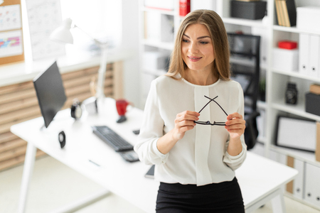 Beautiful young blonde girl in white blouse and black skirt is working in the office. photo with depth of fieldの写真素材