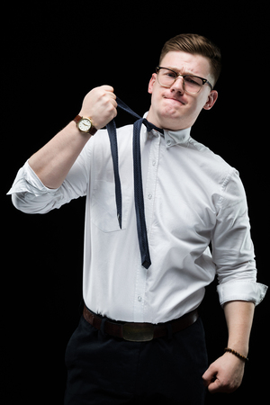 Young caucasian elegant exhausted smart business man in white shirt and tie standing in office looking away tighten a tieの写真素材