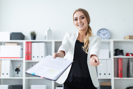 Beautiful young girl with blond hair in a white jacket and black blouse is working in the office. photo with depth of fieldの写真素材