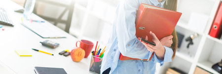 Charming red-haired young girl in a blue blouse is working in a bright office. photo with depth of...