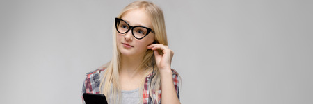 Charming blonde with long hair. A teenager with glasses. Teenager in a plaid shirt.の写真素材