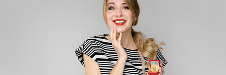 Portrait of beautiful caucasian friendly positive funny woman standing in studio looking in camera with red lips in bright clothes showing currencyの写真素材