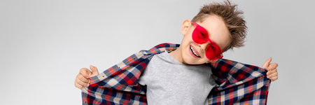 Charming happy child on gray background. The boys hair is up. The boy has a hairstyle. The boy is happy.の写真素材