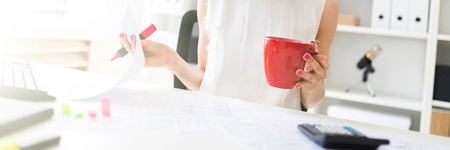 A charming young girl in glasses and a white blouse is sitting in the office at the computer desk. photo with depth of field.の写真素材