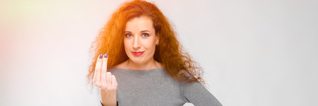 Charming young girl with red hair. A young girl in a gray sweater. Young girl on a gray background.の写真素材