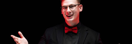 Young caucasian elegant serious smart successful business man in black suit with bow-tie standing in...