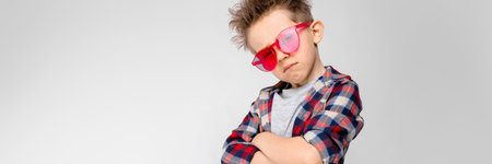 Charming happy child on gray background. The boys hair is up. The boy has a hairstyle. A boy in red...