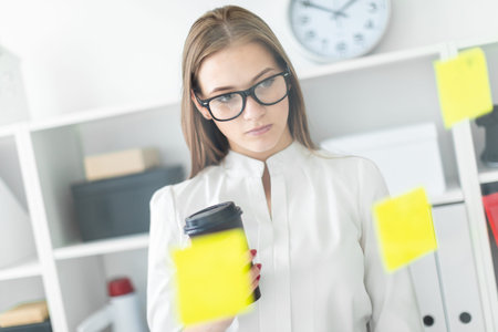 Charming young girl working in a bright office. Young girl in white blouse and black trousers. She...