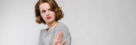 Beautiful young girl posing on gray background. The girl shows the palm