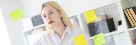 Cute young girl working in a bright office. shes behind the glass with the stickers. The girl is...