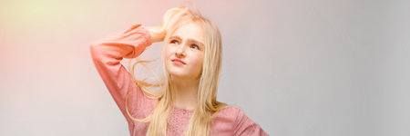 Portrait of a teenage girl. Light long hair. A teenage girl in a pink shirt and blue jeans stands...