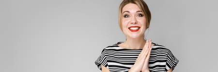 Portrait of beautiful caucasian friendly positive funny woman standing in studio looking in camera with red lips in bright clothesの写真素材