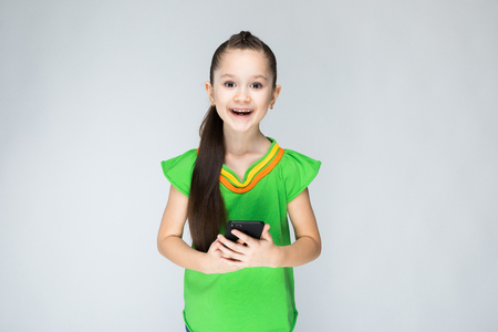 Girl in green t-shirt and blue jeans on grey background.の写真素材