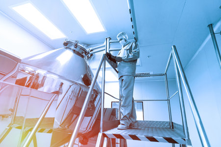 caucasian scientist in blue lab suit and gloves stand on steel ladder and make notes about chromed...