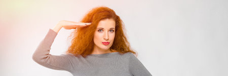 Charming young girl with red hair. A young girl in a gray sweater. Young girl on a gray background.