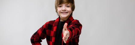 Portrait of small adorable thoughtful stylish confident caucasian guy standing in studio looking in camera happyの写真素材