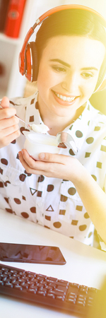 Beautiful young girl in a white blouse in a geometric pattern and blue jeans. Girl with dark hair and beautiful make-up. A charming young girl is working in a bright office. photo with depth of field.の写真素材