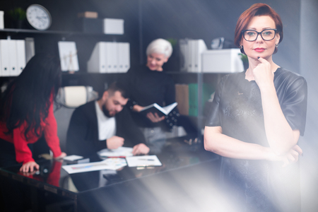 Beautiful Young woman on background of workers conducting meeting. group of successful businessmen.Business group discussion concept. glow at bottom of imageの写真素材