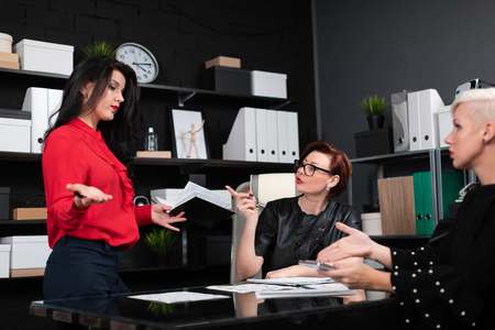 group of successful businessmen. concept of reliable partnership. Business partners work with documents at office Desk. Three women discuss marketing planの写真素材