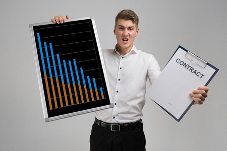 man in a shirt with a Board with statistics and blank contract form in his hands isolated in a light Studio. Graphics colorful for display white poster. rising, falling and with percentages diagrams showing business progress and regressionの写真素材