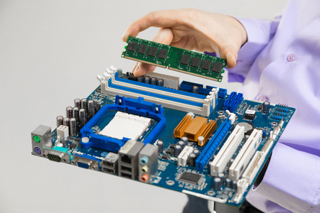 Close-up computer RAM and motherboard isolated on a white background. Details from the computer in mens handsの写真素材