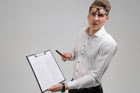 handsome man in white shirt is holding sheet of insurance in his hands. Insurance agents alone with Studio. place for labelの写真素材