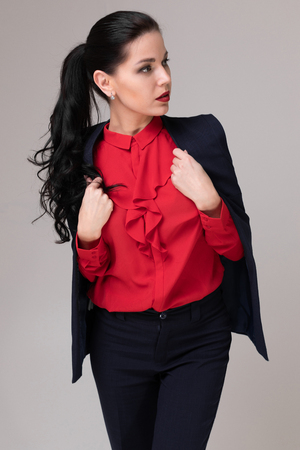 Portrait of a charming girl in the Studio on a white background. macrophotography friendly businesswoman in a red blouse and a black vest. Business concept. Concept of educationの写真素材
