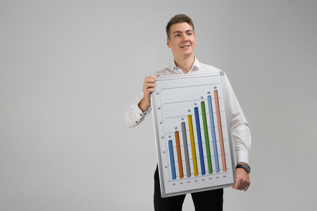 man in a shirt with a Board with statistics in his hands isolated in a light Studio. Graphics colorful for display white poster. Round, triangular, rising, falling and with percentages diagrams showing business progress and regressionの写真素材