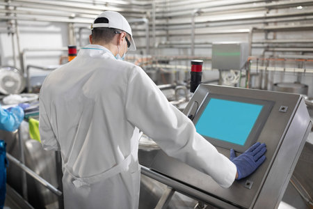 concentrated technologist taking necessary notes with help of digital tablet while standing at...