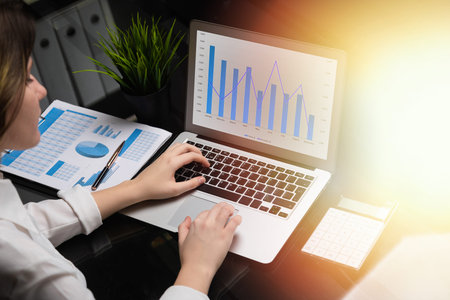 Business lady works on laptop with blank black screen, analyzing charts. Modern laptop and...