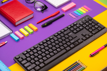 Top view, flat lay of business desk composite with stationery, keyboard, diary, and pen on colorful background as part of business conceptの写真素材