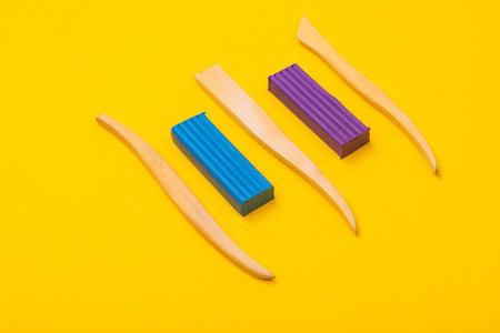 top view of blue and purple pieces of plasticine and wood cutters lie isolated on a bright background. Place for writing. Can be used as a creative background. Modeling of clayの写真素材