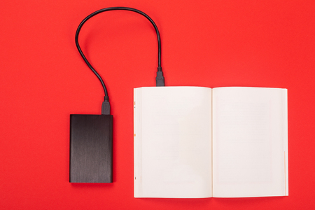 transfer of information from digital media to a piece of paper via a USB cable. the black power Bank is connected by a wire with an opened Notepad. A place for a labelの写真素材