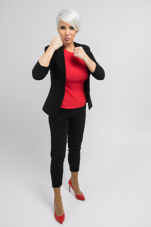 charming blonde in a black fashionable suit stands and looks at the camera in isolation on a white background.Young pretty businesswoman isolated on white background. Full height portraitの写真素材