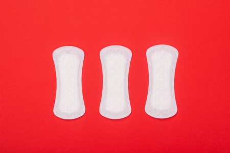 Three white sanitary pads on red background, copy space for text. health and medicine. Feminine hygiene. Menstrual pad on red backgroundの写真素材