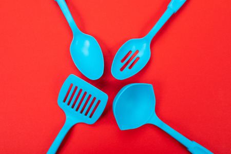 Four kitchen tools lie in the center of the image isolated on a red tablecloth. Kitchen accessories...