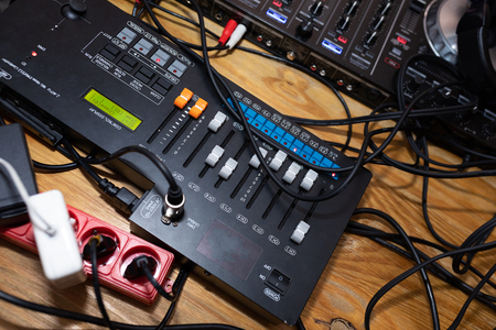 DJ music console, laptops and headphones in bright colors of light in night club bright red-blue...