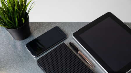 tablet with a black blank screen and other documents are on a gray Desk in the office. Business concept. A place for a labelの写真素材