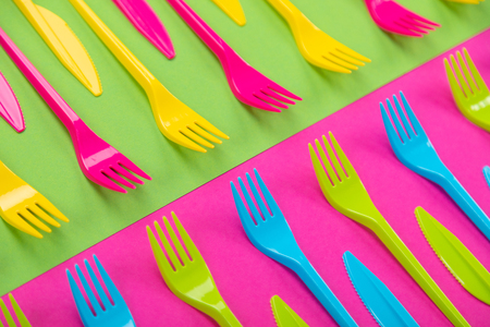 Composition of colorful plastic cutlery on a bright background top view