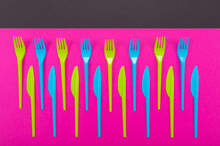 Composition of colorful plastic cutlery on a bright background top view