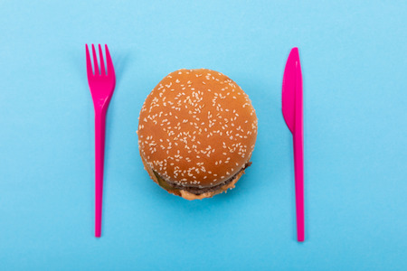 Plastic set of fork and knife with tasty burger. Mock-up