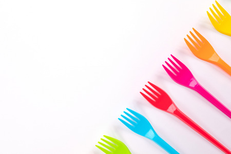 Composition of colorful plastic forks on a bright background top view
