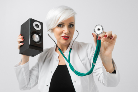 confident blonde woman with speakers in hands in white dressing gownの写真素材