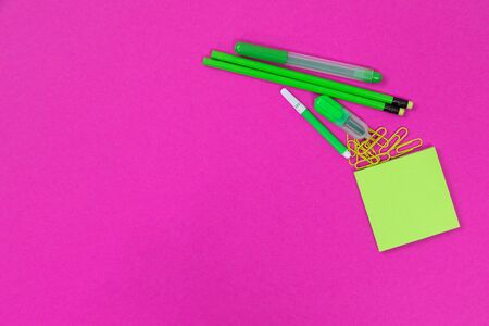 A group of light green writing equipment is lying in the top right corner on pink surface cutoutの写真素材