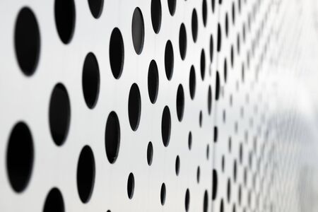 Rapid black big dot pattern on white background, round holes texture on perforated metal panel surface, angle view.の写真素材