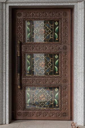 Dark brown wooden door with wood engraving and colored glassの写真素材