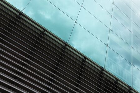 Diagonal view of modern wall surface, glass and metal texture with sky reflection