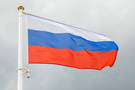 Russian flag on a flagstuff in front of the skyの写真素材