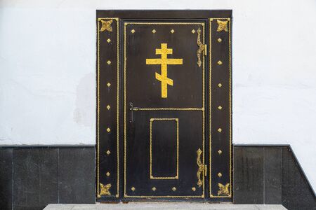 Old black wooden church door in white wallの写真素材