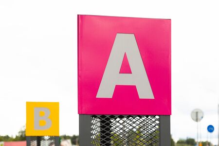 Tablet with letter A on pink backdrop and behind letter B on yellow background defocused